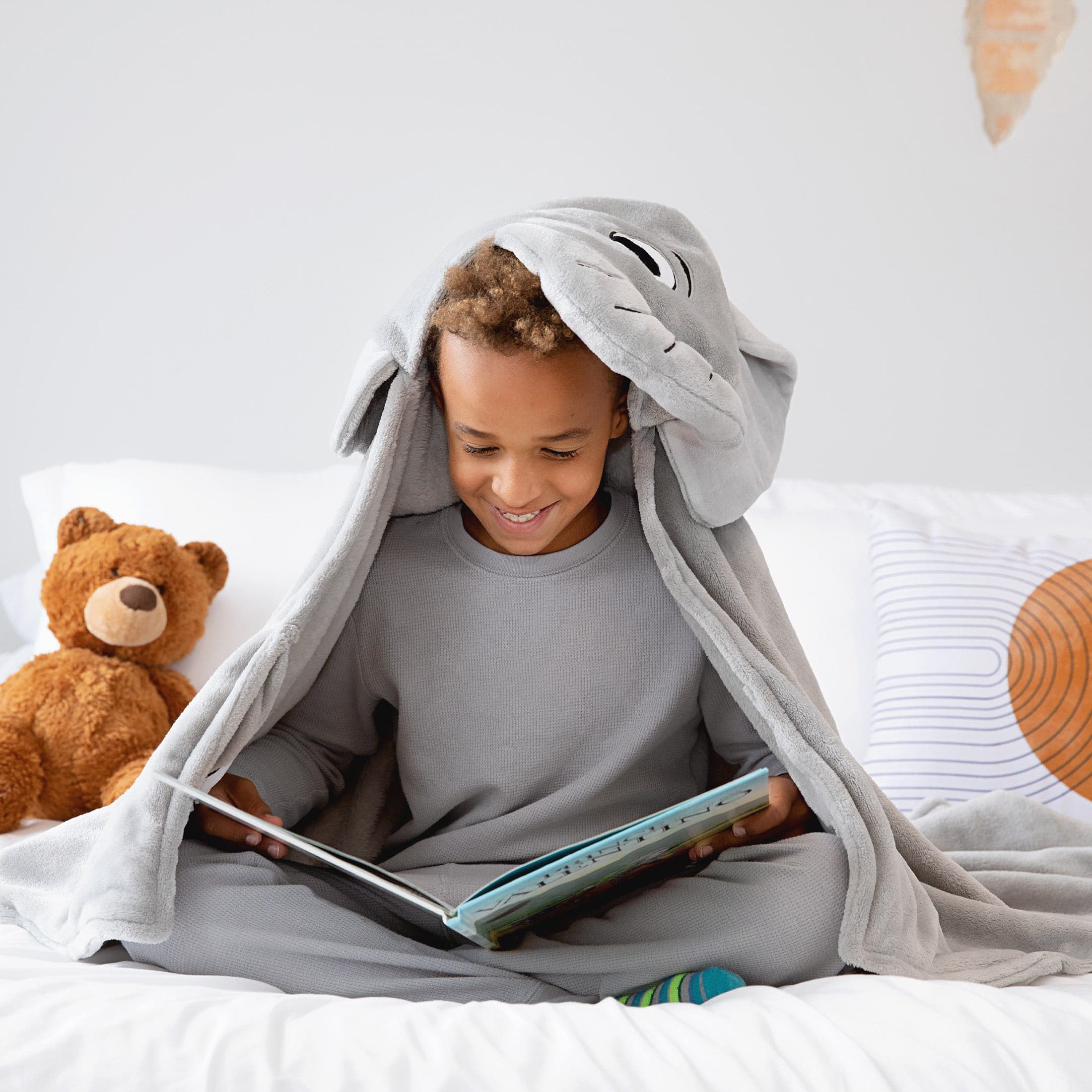 Child in an elephant Canoogles blanket reading a book
